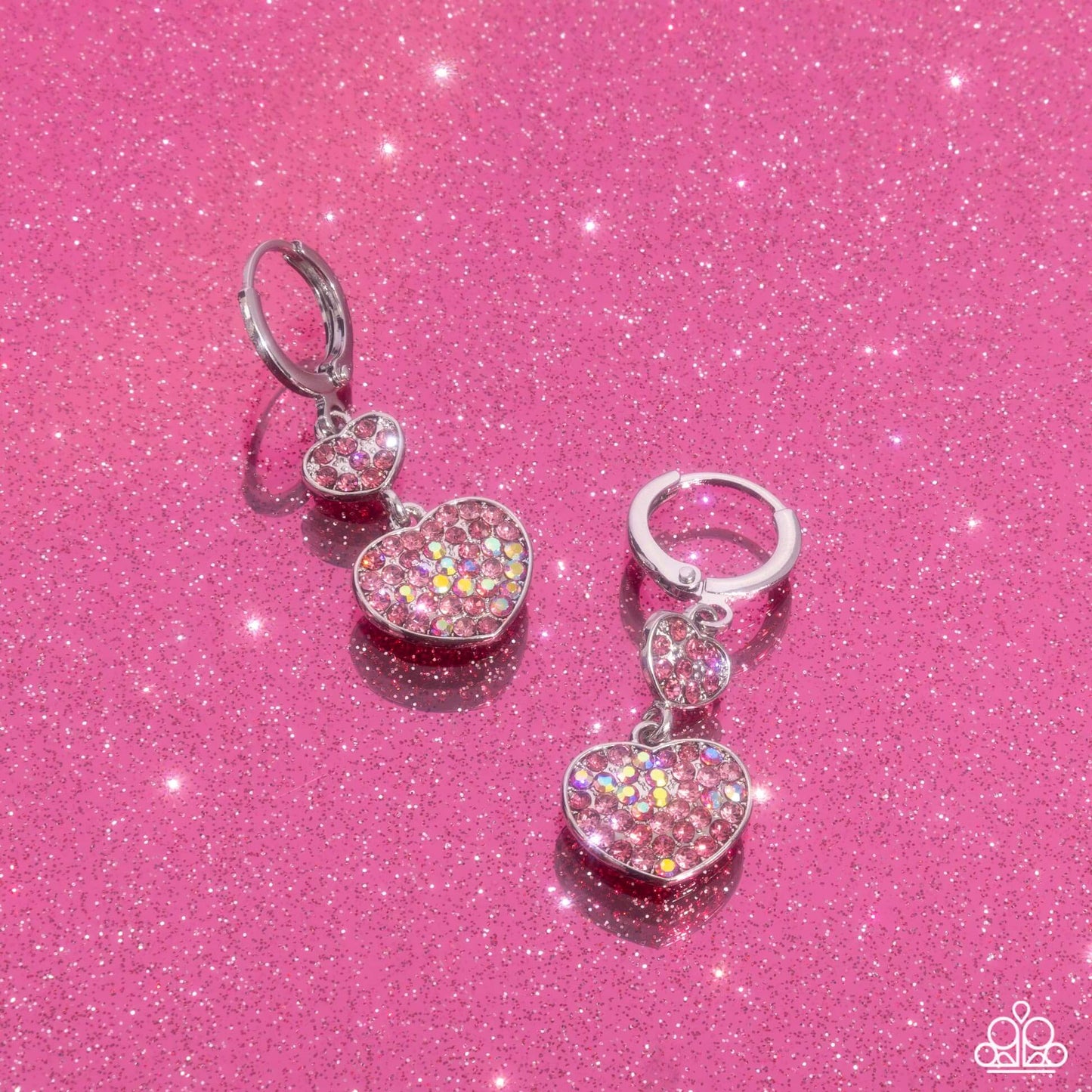 Sparkling pink Paparazzi heart earrings with rose rhinestones on a glittery pink background, perfect for Valentine's Day.