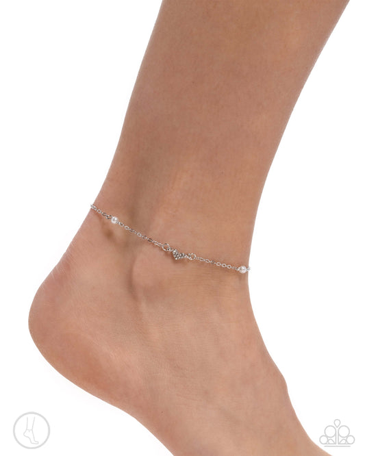 Dainty white pearl and silver heart anklet on model's ankle with adjustable clasp closure.